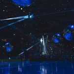 a group of people standing on top of a blue floor